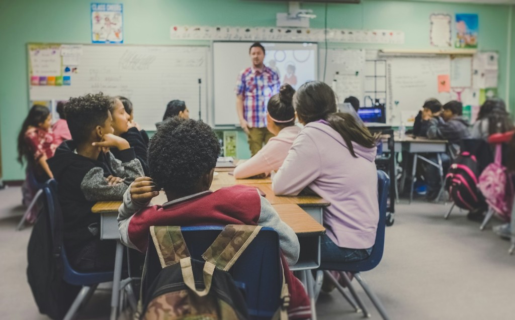 Students learning together in a classroom with their teacher at the front
